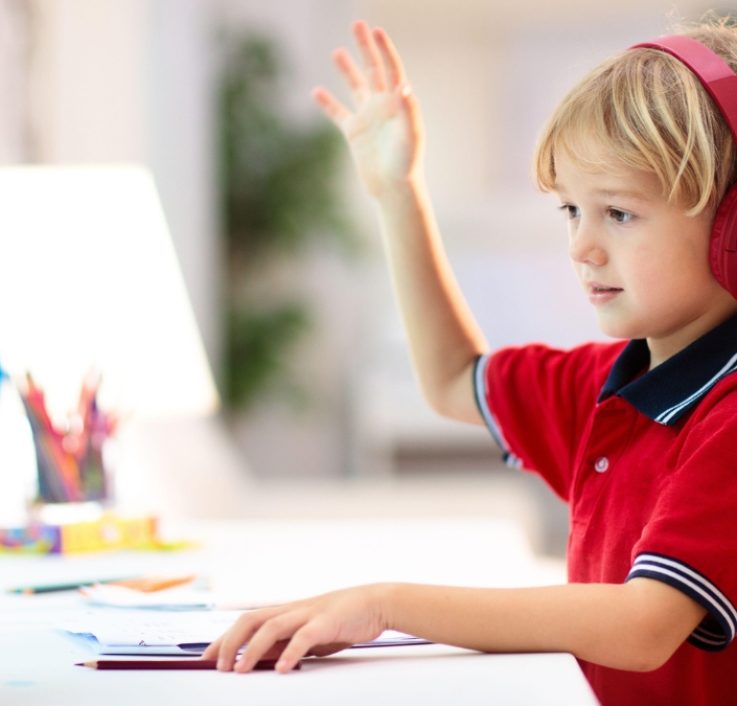 A young child aged 4–6 reading a book with confidence, bright and warm setting. Young child building early reading skills through online phonics classes